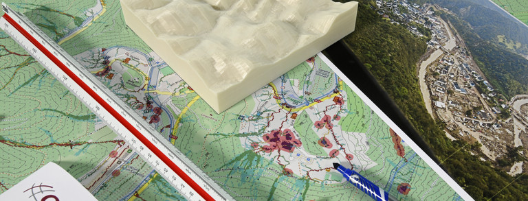 Bauplan mit 3D Höhemodell, Landschaftsbildern und Stiften.
