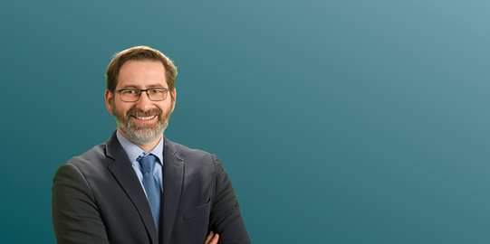 Professor Thomas Hartmann in front of a blue background