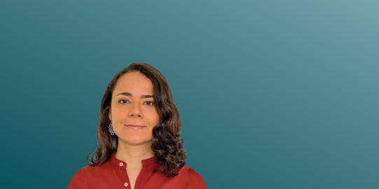 Tatiana Moreira de Souza in front of a blue background.