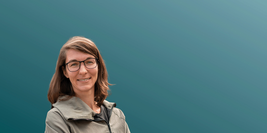 Denise Ehrhardt in front of a blue background.