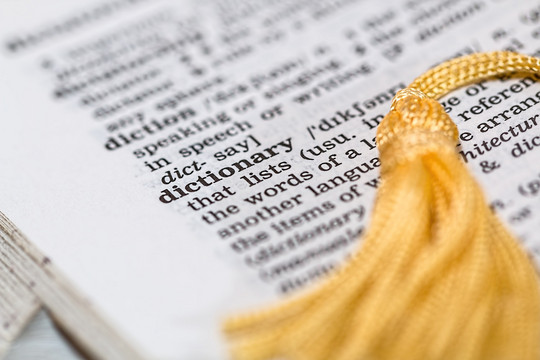 An open page of an english dictionary with a yellow bookmark.