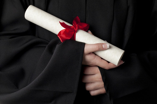 A rolled document with red bow is held by hands. 